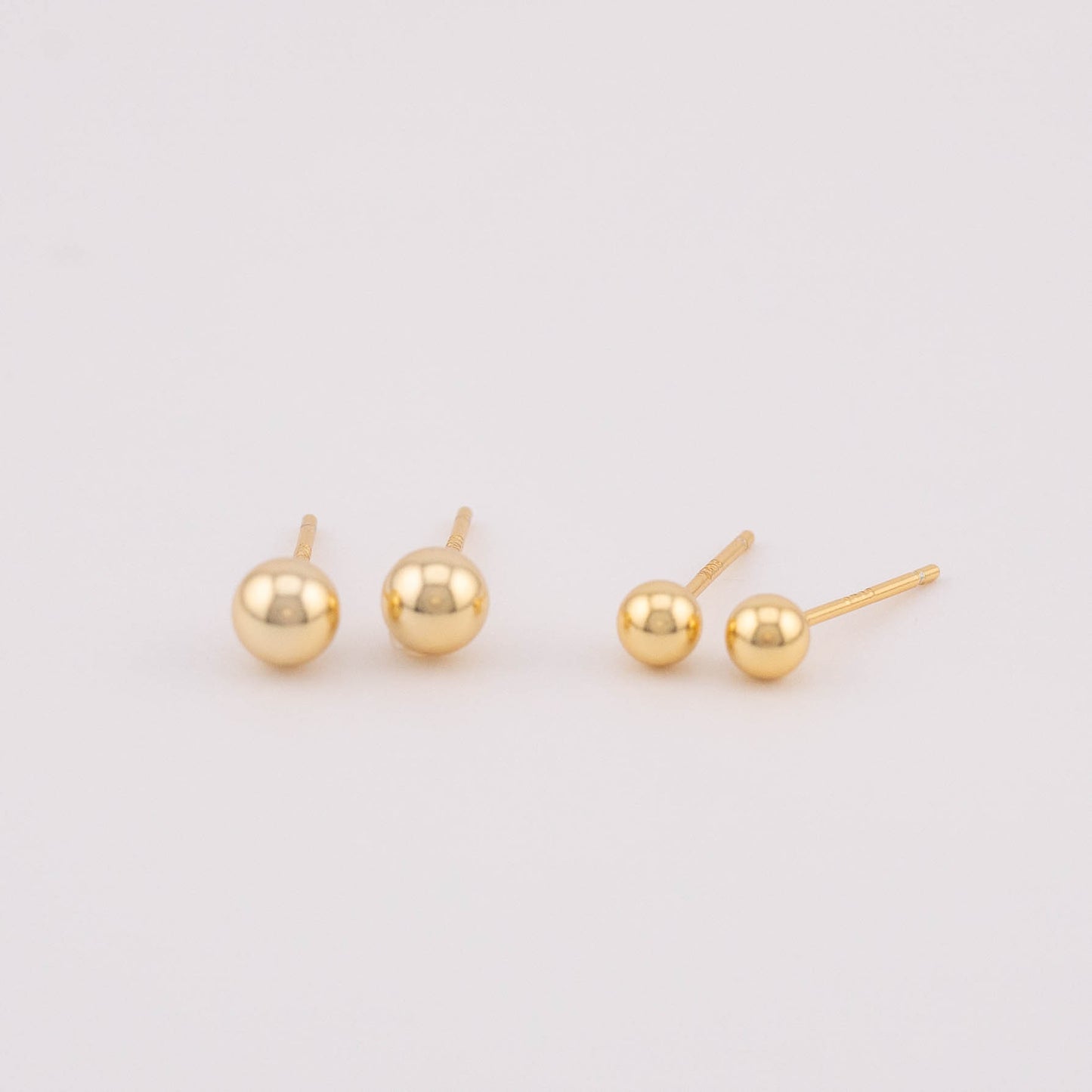 Front view photo displaying two sets of gold ball earrings with varying sizes, positioned side by side for easy comparison. Ideal for selling as a set, showcasing the versatility in size options and offering a stylish addition to any jewelry collection.