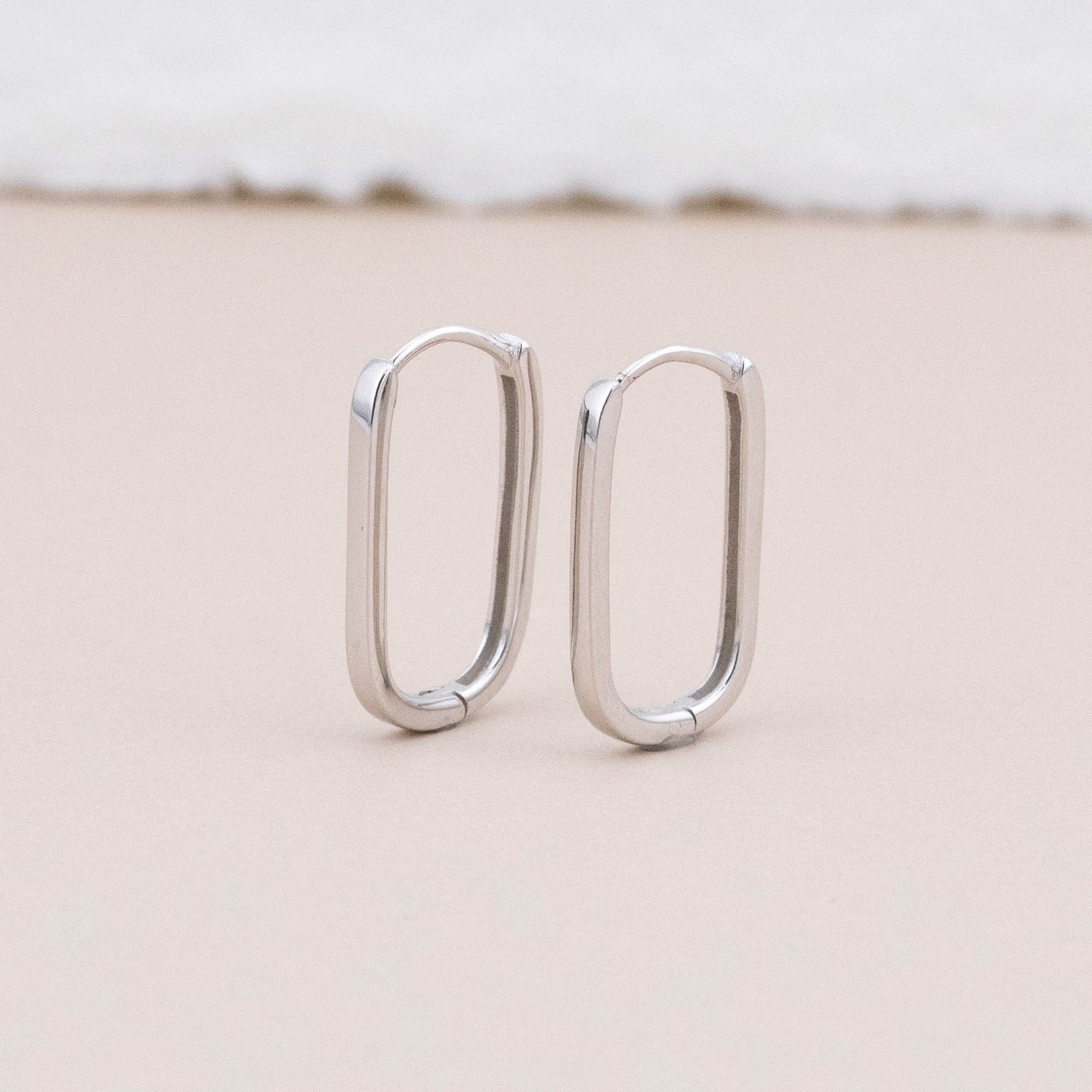 Sterling silver mini huggie hoop earrings standing, highlighting their sleek and modern design.