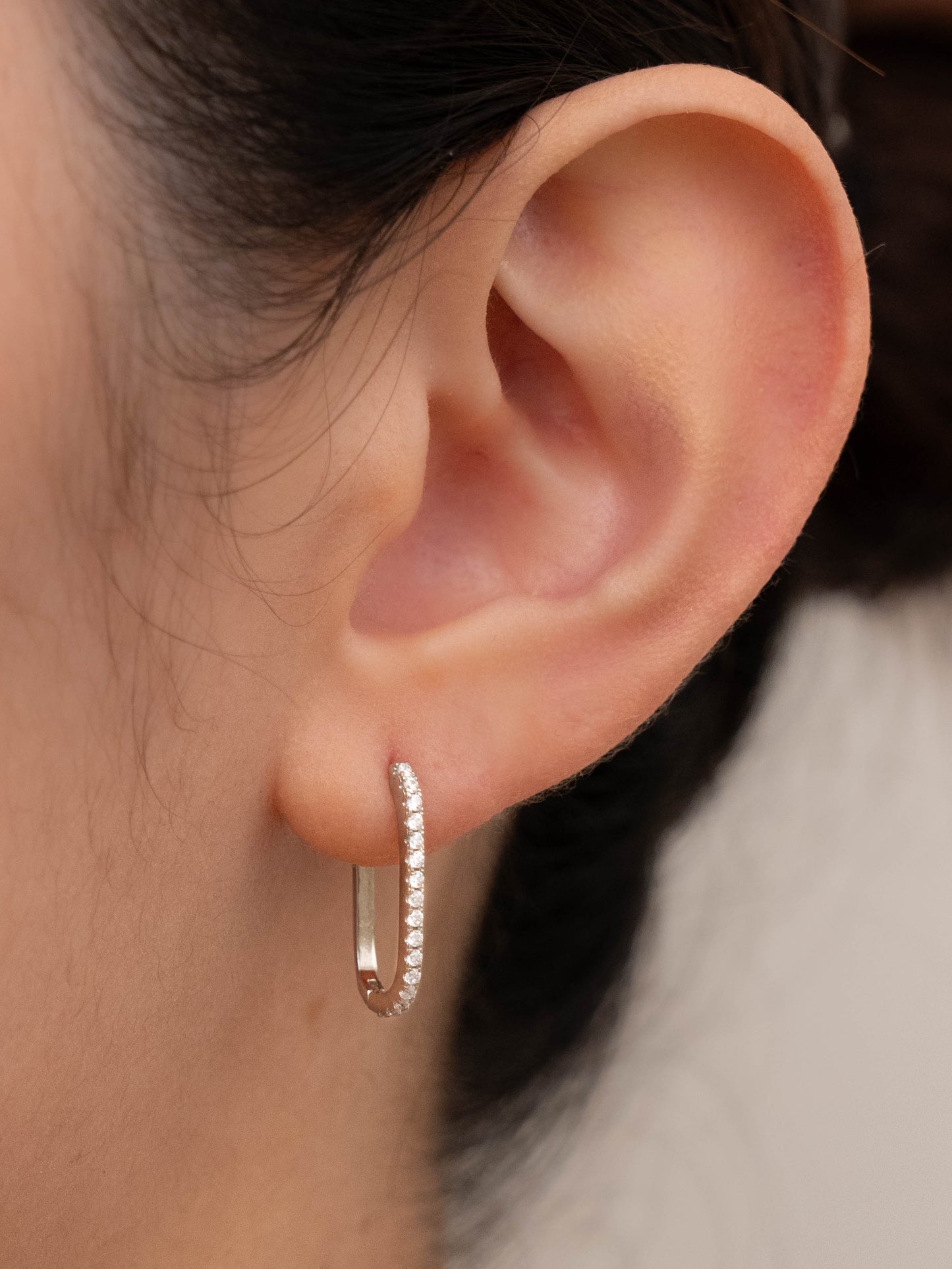 Square silver earring in one ear, showing its appearance when worn.