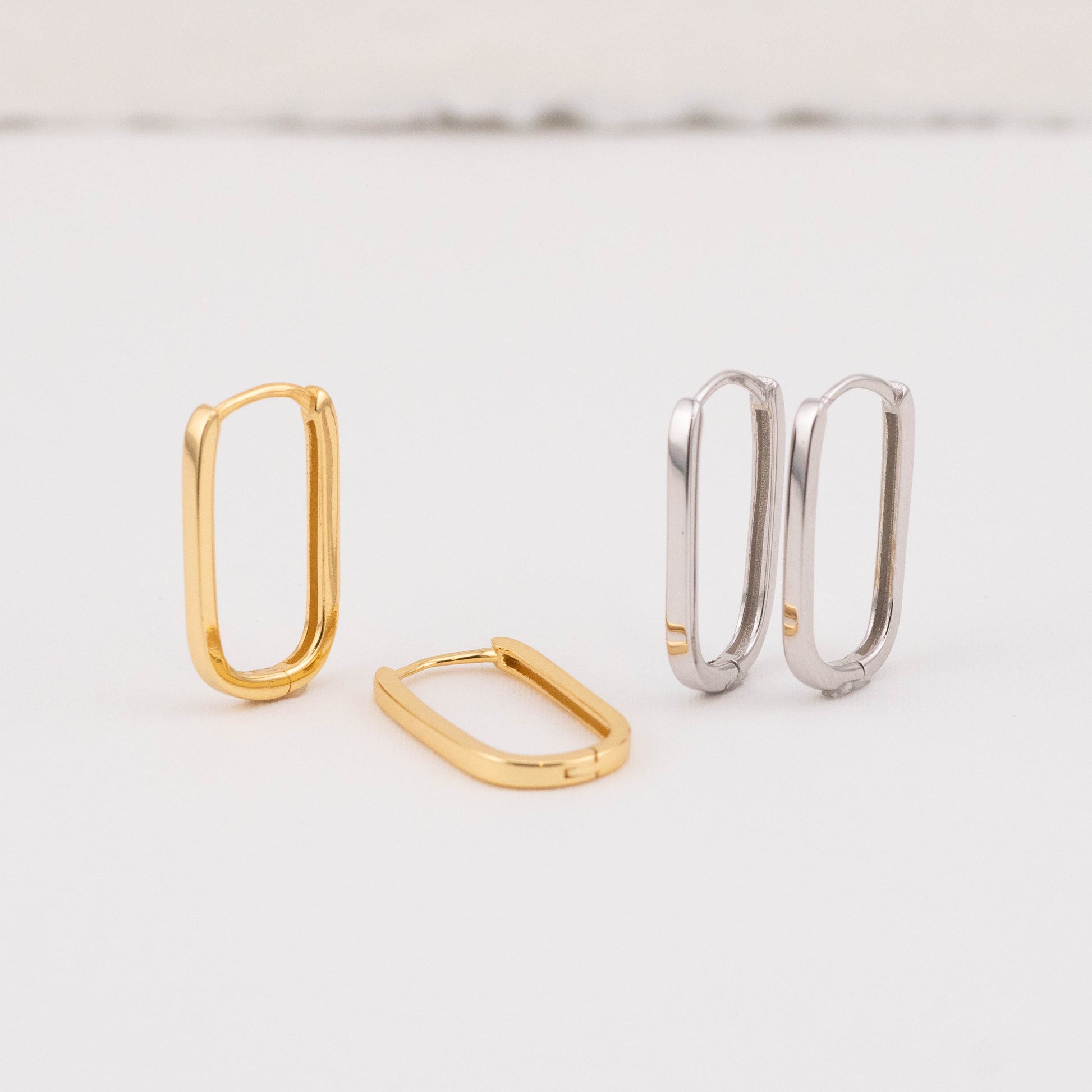 Front angled view of oval hoop earrings in 14k gold vermeil and sterling silver, featuring their dual-tone design.