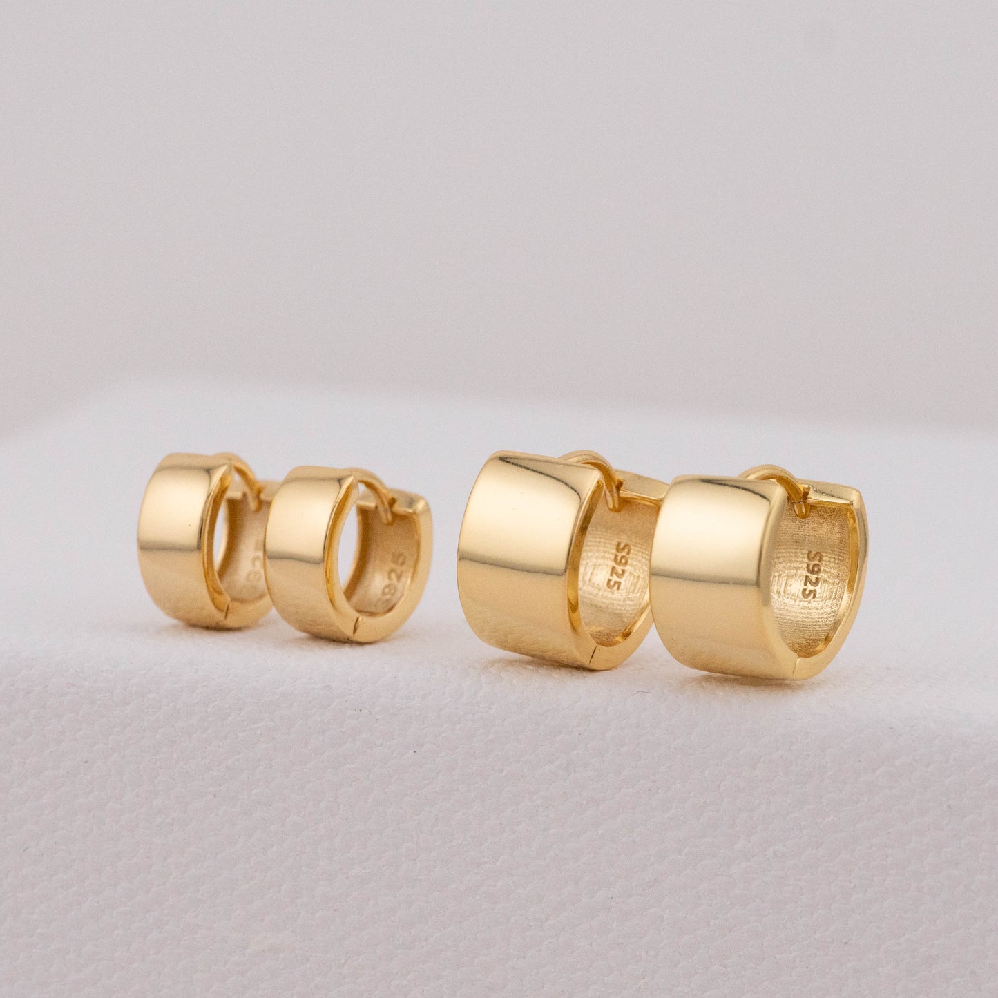 Bold huggie hoops in gold, showing 8mm and 11mm pairs seated side by side.