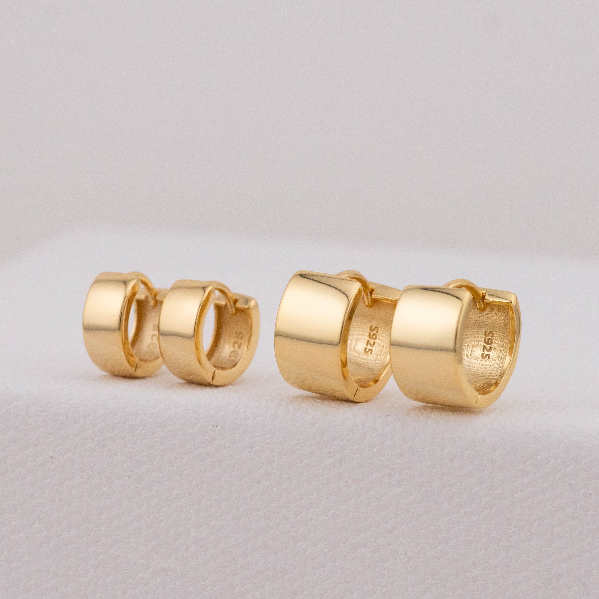 Bold huggie hoops in gold, showing 8mm and 11mm pairs seated side by side.