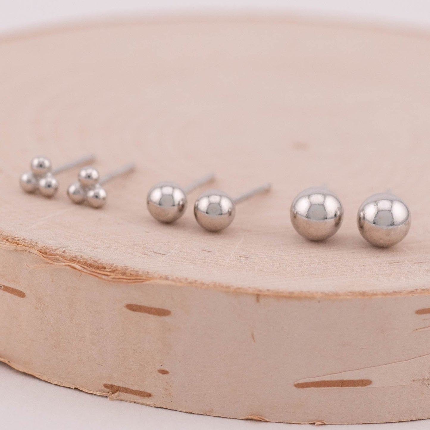 Three sets of silver ball stud earrings arranged side by side, captured from a 45-degree angle to reveal both the front and back of the earrings. A versatile choice for adding subtle elegance to any ensemble