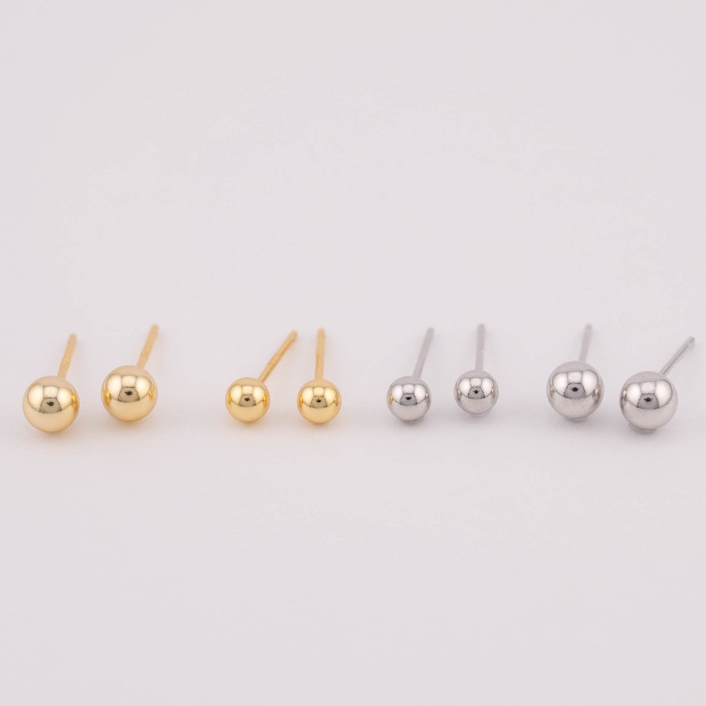 Front view photo featuring four sets of gold and silver ball earrings with two different sizes each, arranged side by side for size comparison. Suitable for sale as a set, offering versatility in size options and a stylish addition to any jewelry collection.
