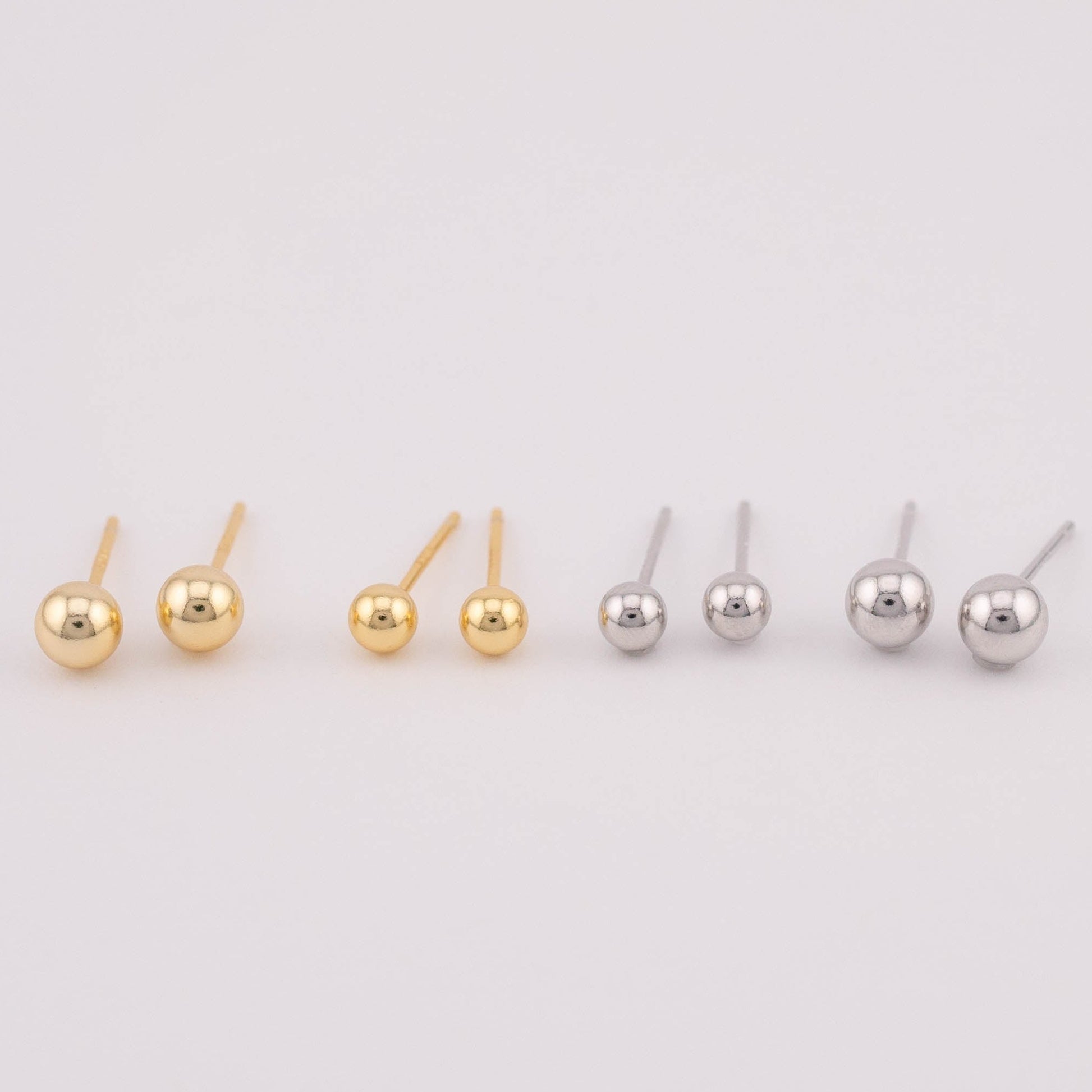Front view photo featuring four sets of gold and silver ball earrings with two different sizes each, arranged side by side for size comparison. Suitable for sale as a set, offering versatility in size options and a stylish addition to any jewelry collection.