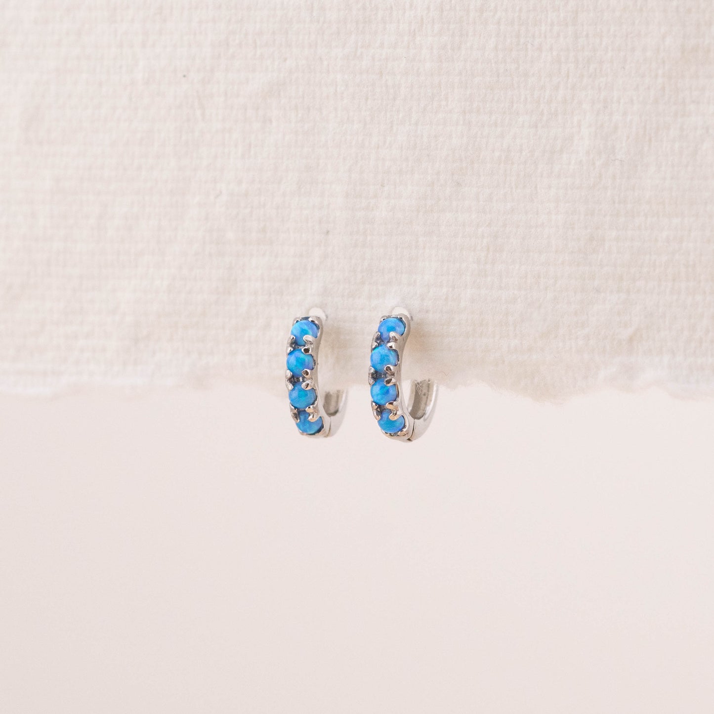 Blue opalescent stone earrings hung on an earring stand, highlighting the unique beauty of natural blue opal stones