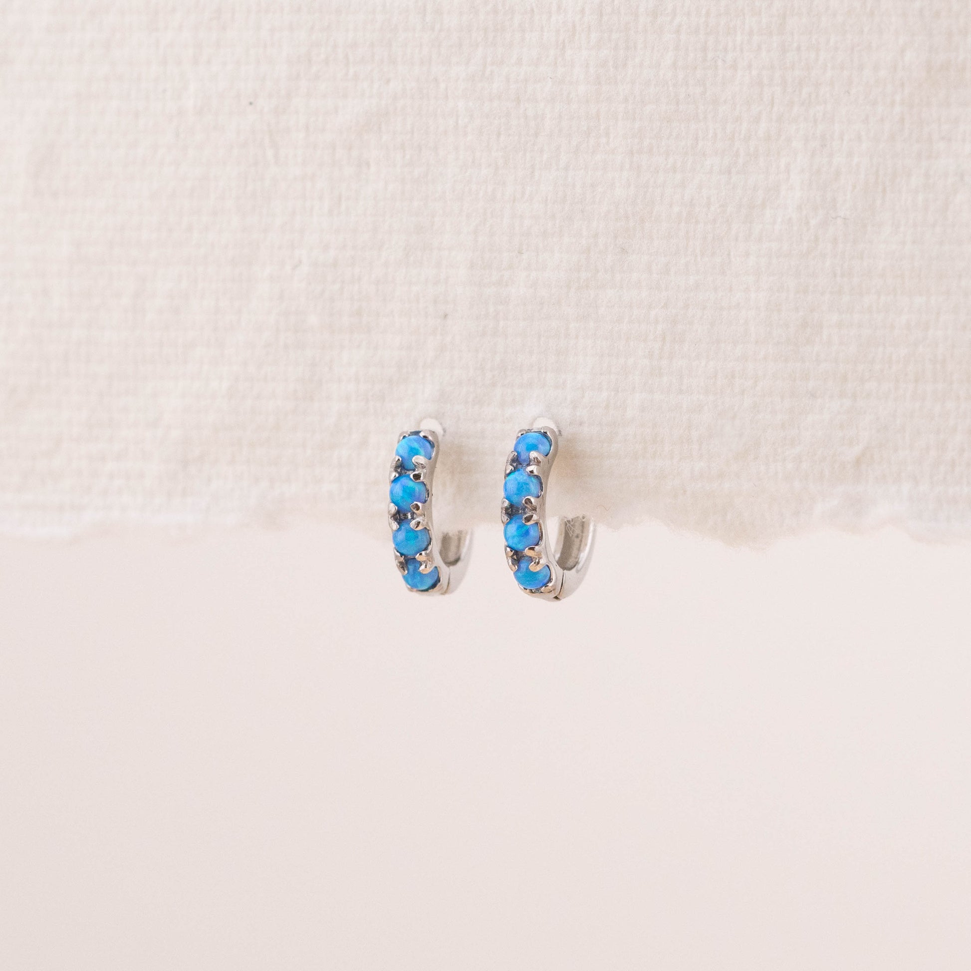 Blue opalescent stone earrings hung on an earring stand, highlighting the unique beauty of natural blue opal stones