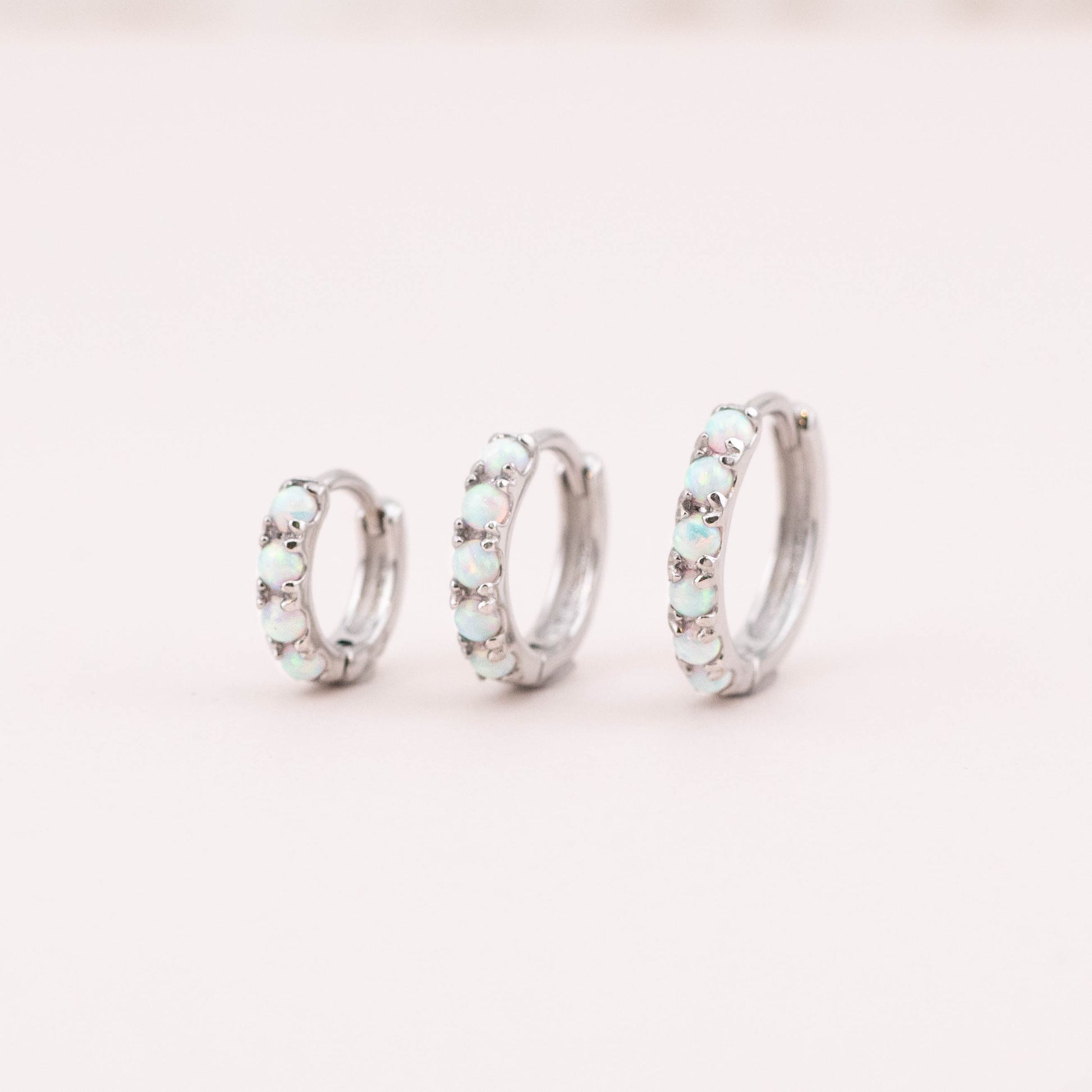 Three opal huggie earrings side by side, varying in size and stones. Angled photo captures complete shape and design