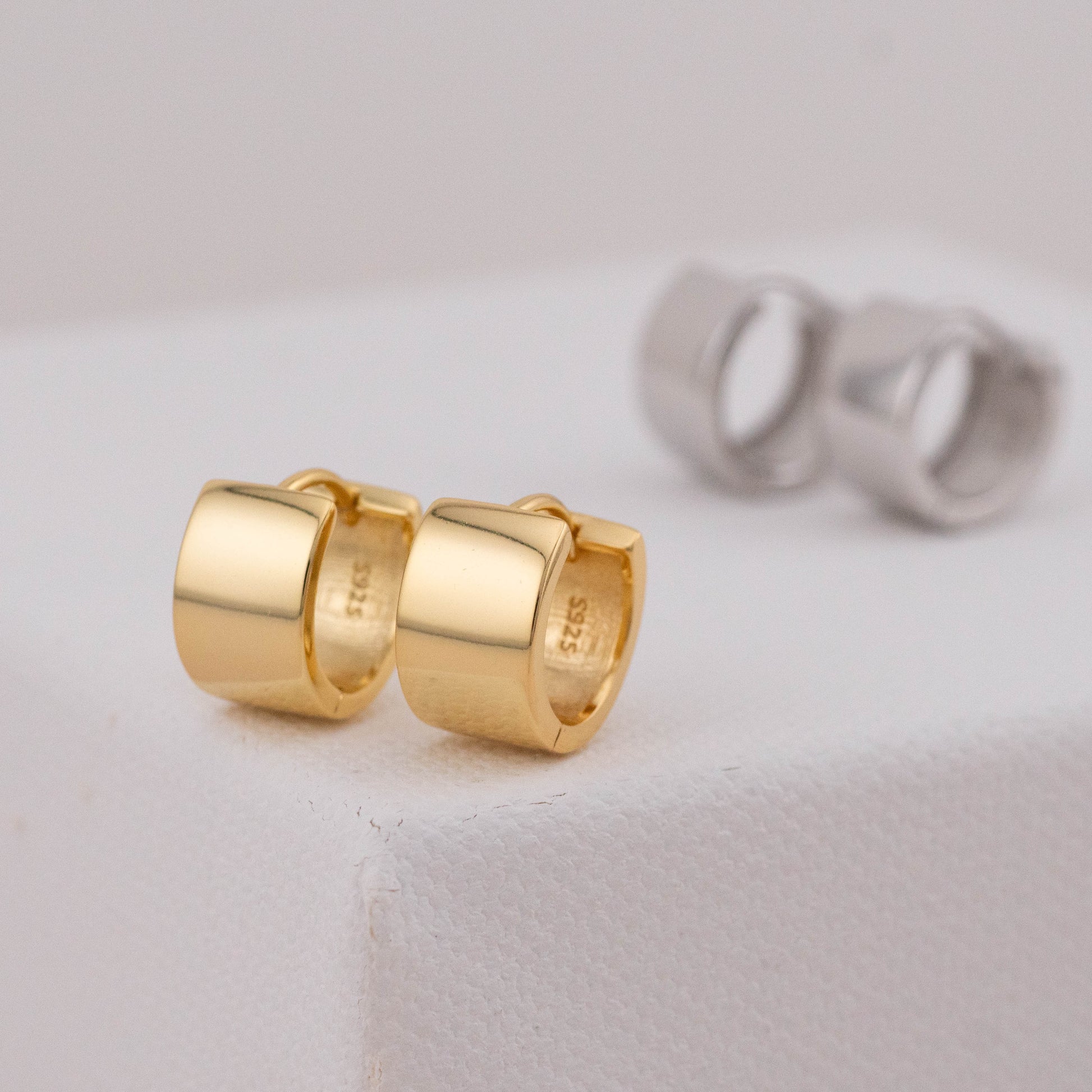 Chubby gold hoops with detailed lock, silver hoops in the background.