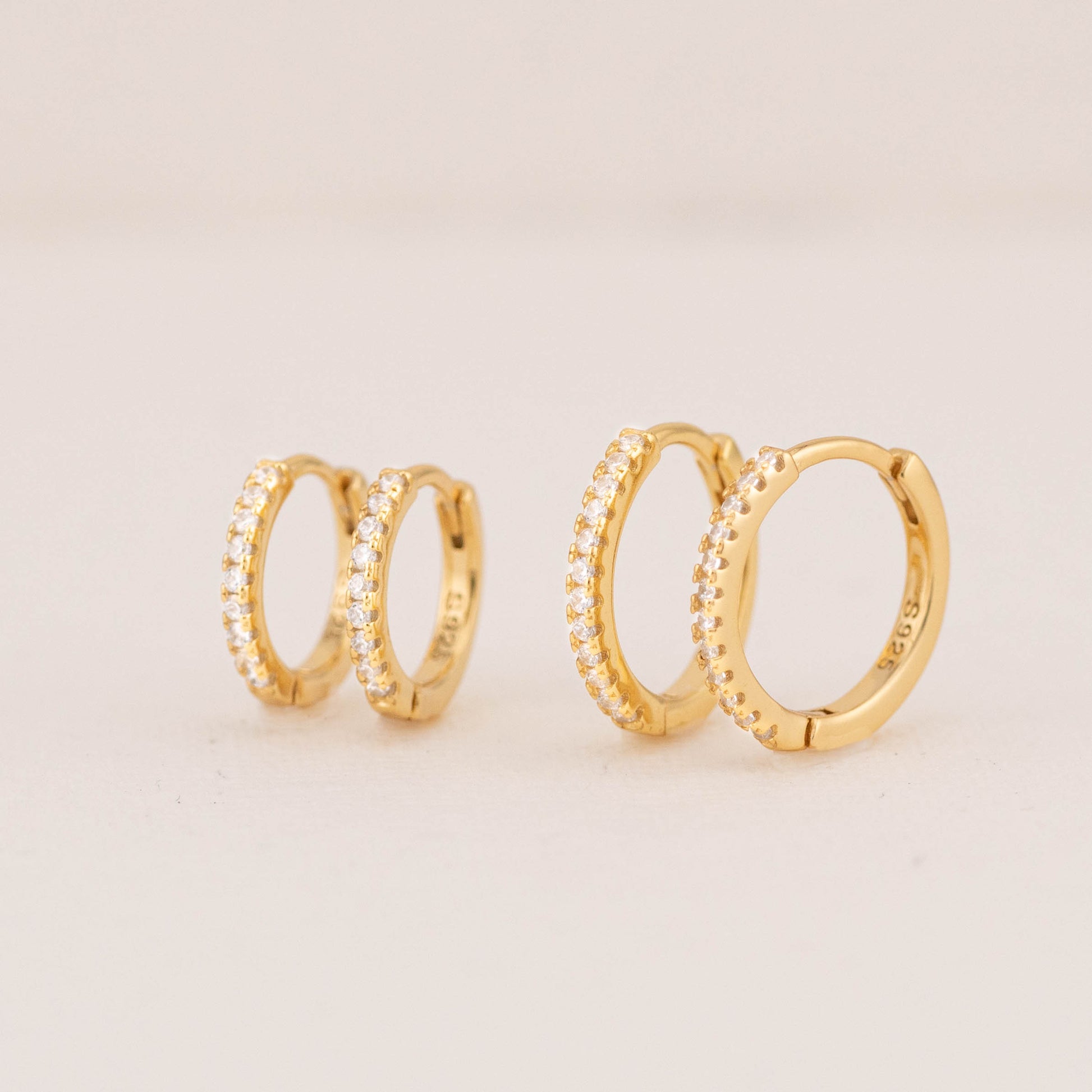 Close-up of gold mini diamond hoops, showcasing chic pave design and secure hinged closure.