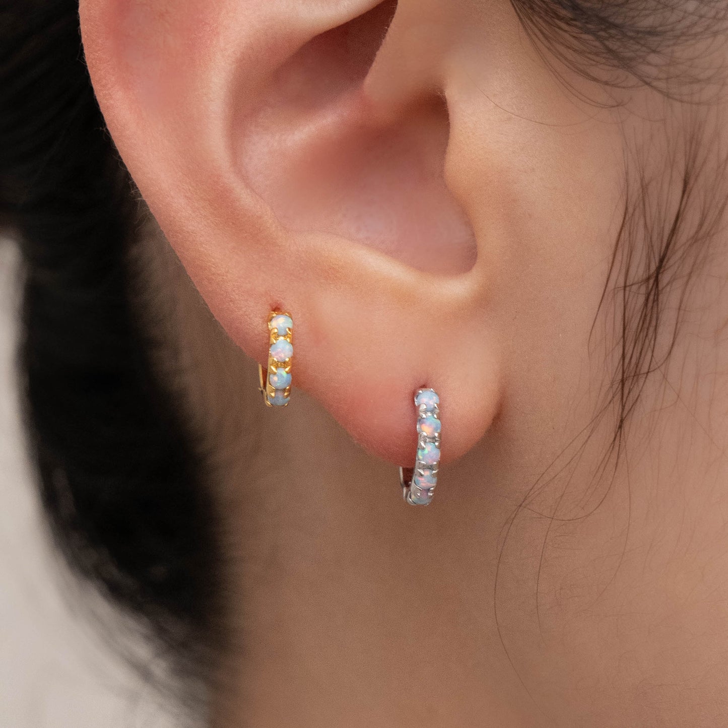 Genuine opal earrings in blue and white worn in one ear, showcasing their natural versatility.