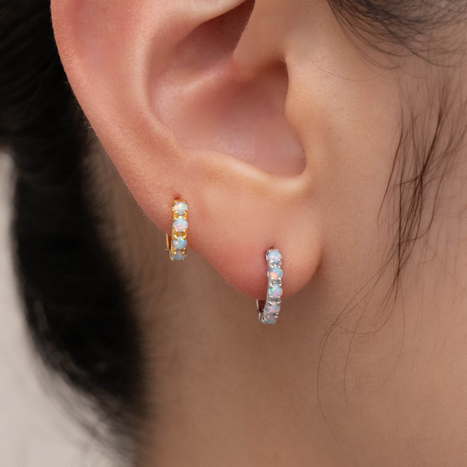Genuine opal earrings in blue and white worn in one ear, showcasing their natural versatility.