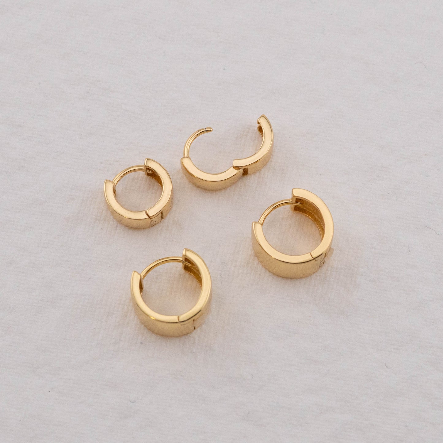 Trendy hoop earrings in gold, showing one earring unlocked to highlight the open and closed look.