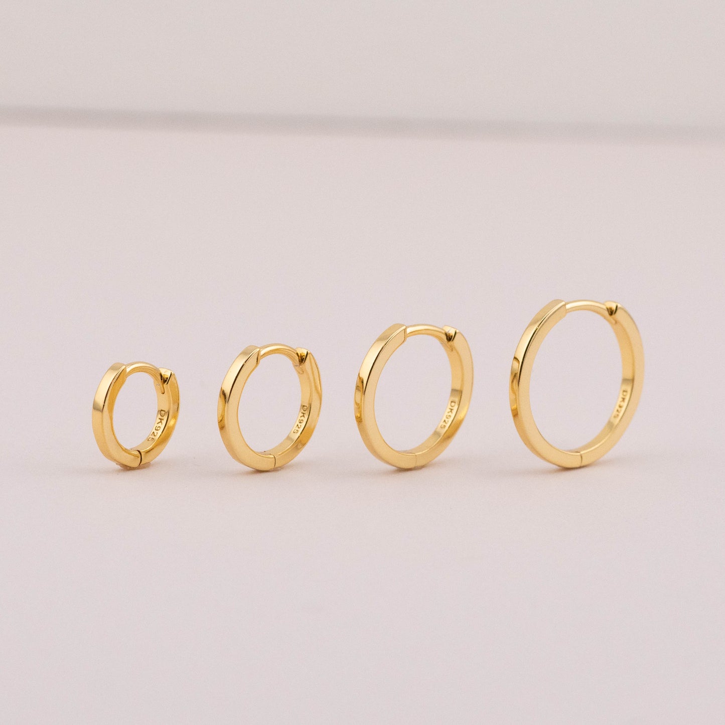 Small huggie hoop earrings in 4 sizes, staged to show shiny, tarnish-free finish for multiple piercings.