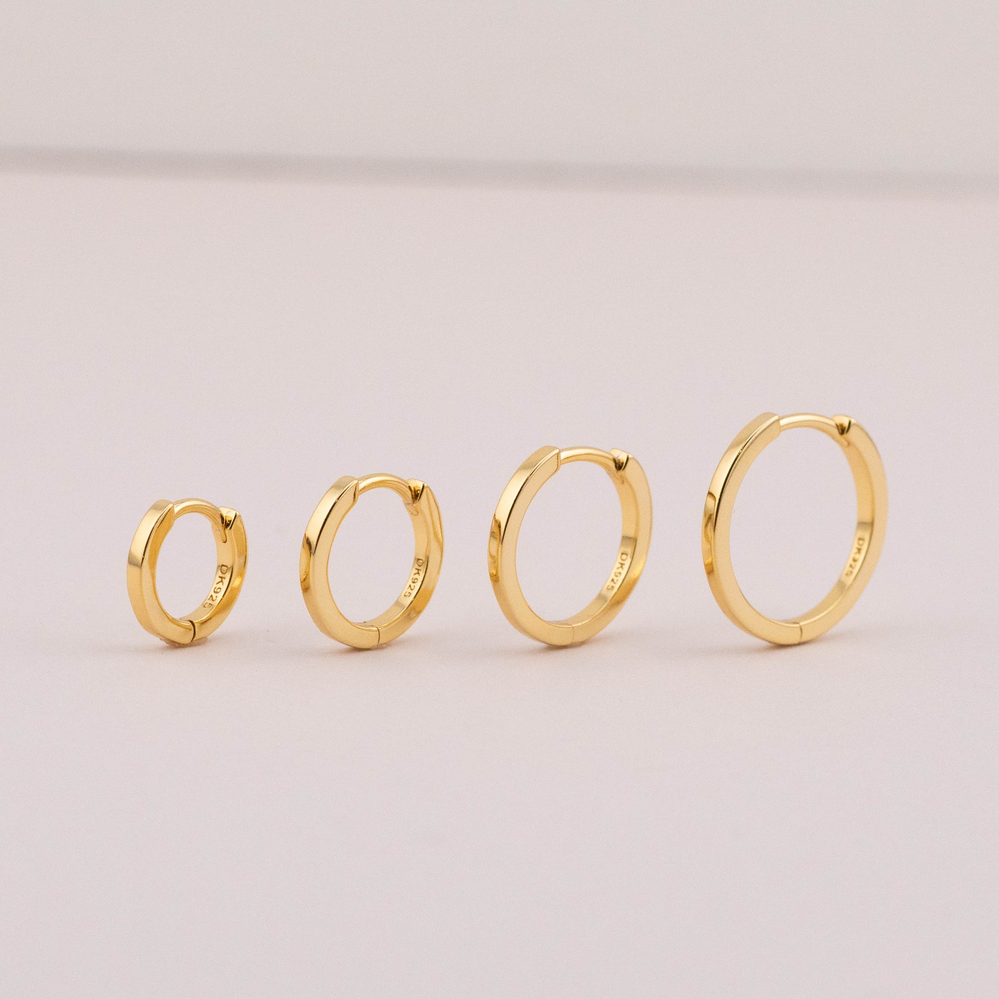 Small huggie hoop earrings in 4 sizes, staged to show shiny, tarnish-free finish for multiple piercings.