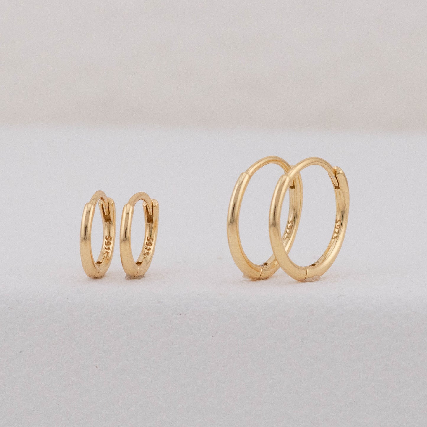 2 pairs of gold hoops in different sizes are displayed, showing stackable earring sets for 2 holes
