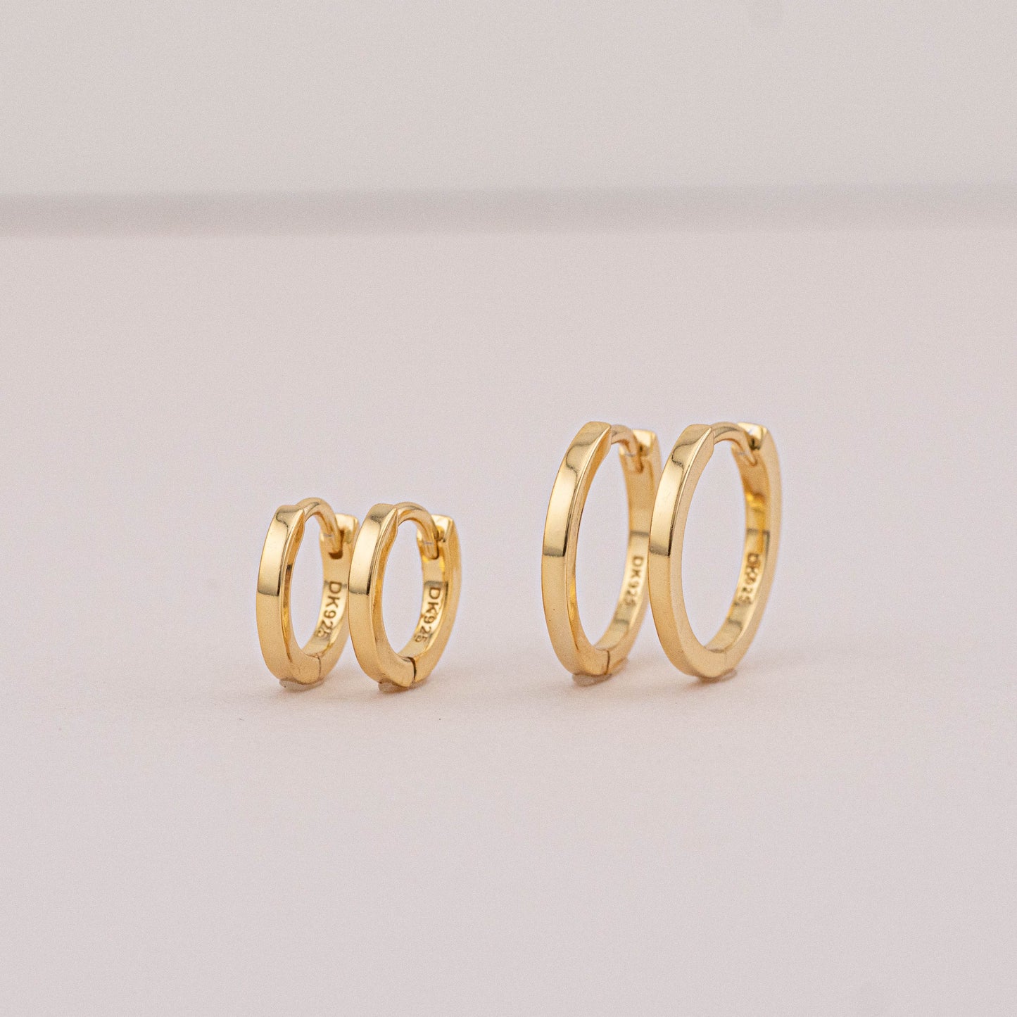 Gold mini huggies for 2 holes, 2 pairs placed on stage to show they can be worn as stack sets