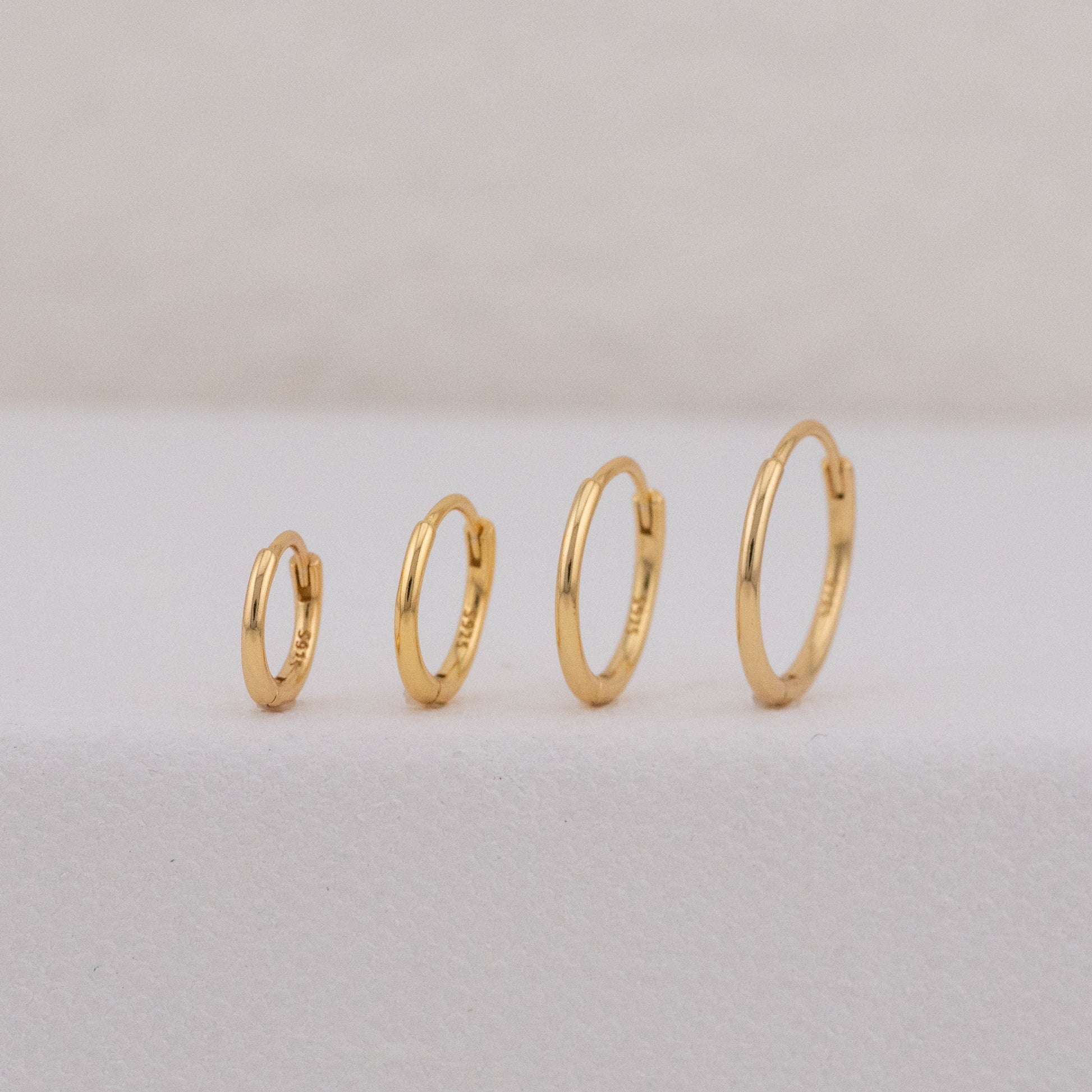 mini hoop earrings in different sizes are standing upright, showing it could be worn as stack sets