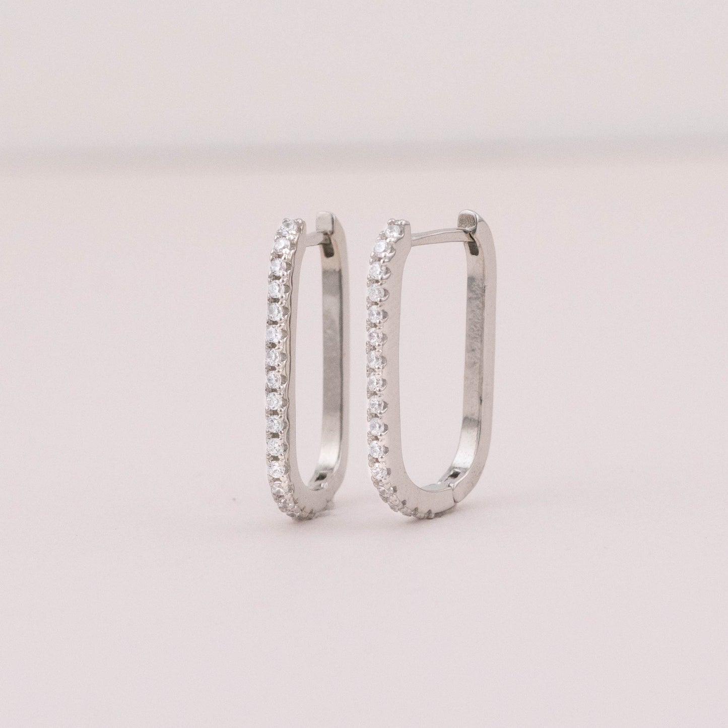 Silver square hoop earrings with small diamond stones, showing front and side view with secure lock.