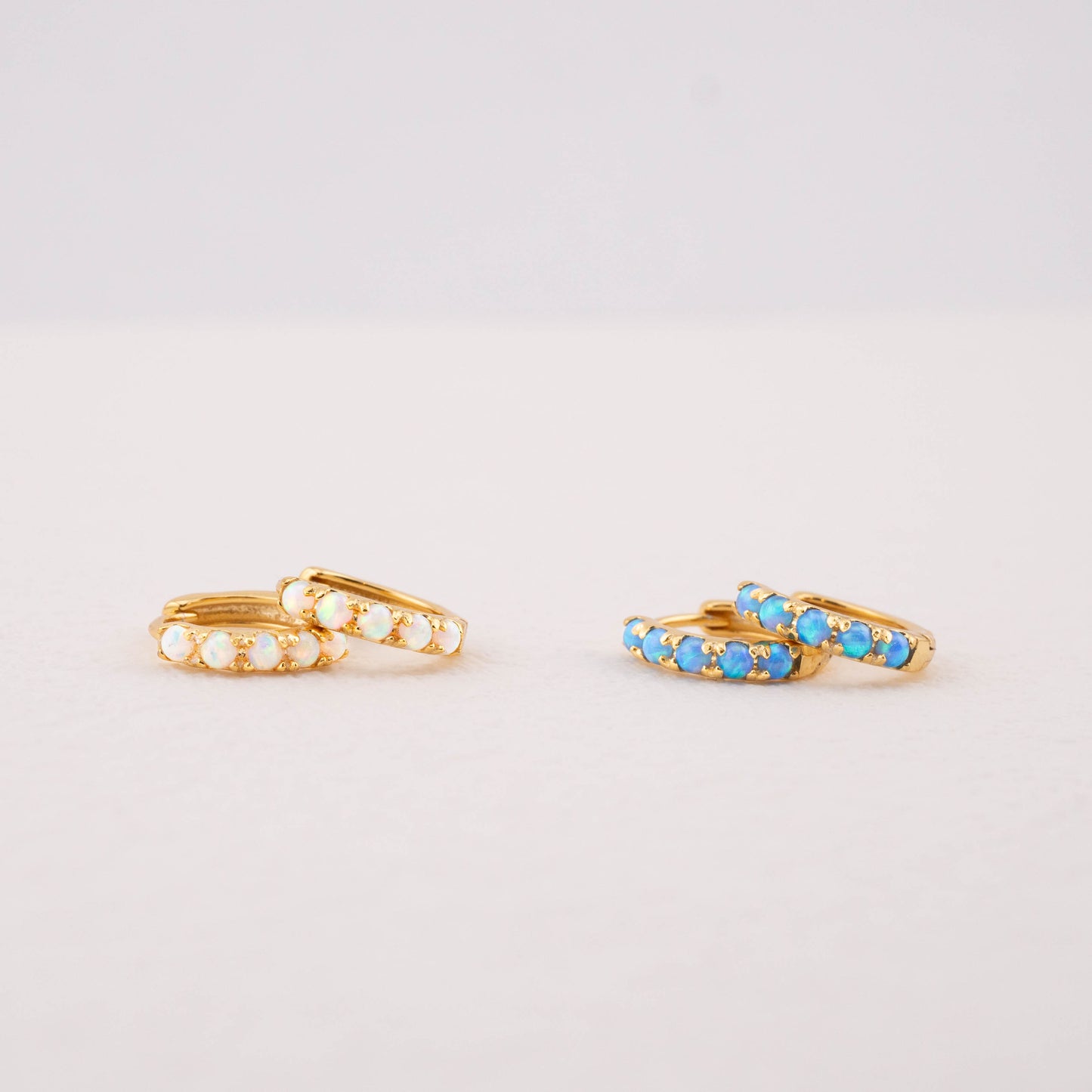 Opal huggie earrings: blue and white opal in gold, showing color differences and details.