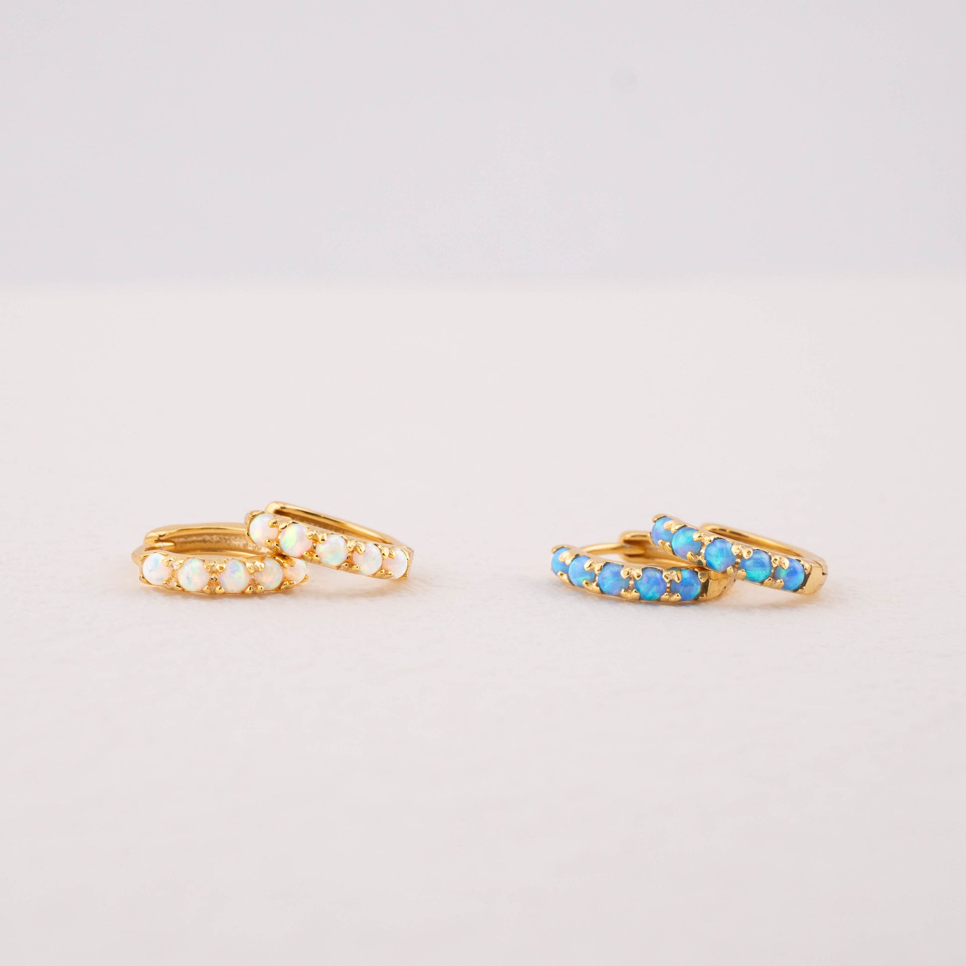 Opal huggie earrings: blue and white opal in gold, showing color differences and details.
