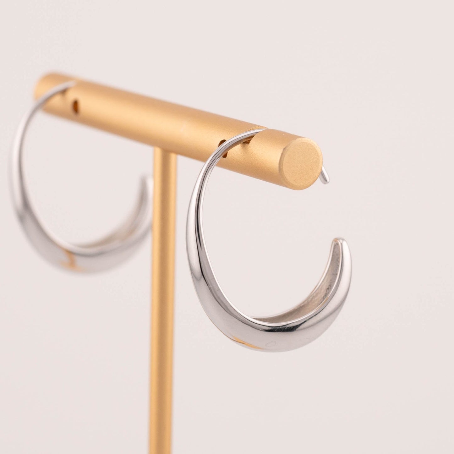 Minimalist medium sized silver ear hoops earrings staged on jewelry stand
