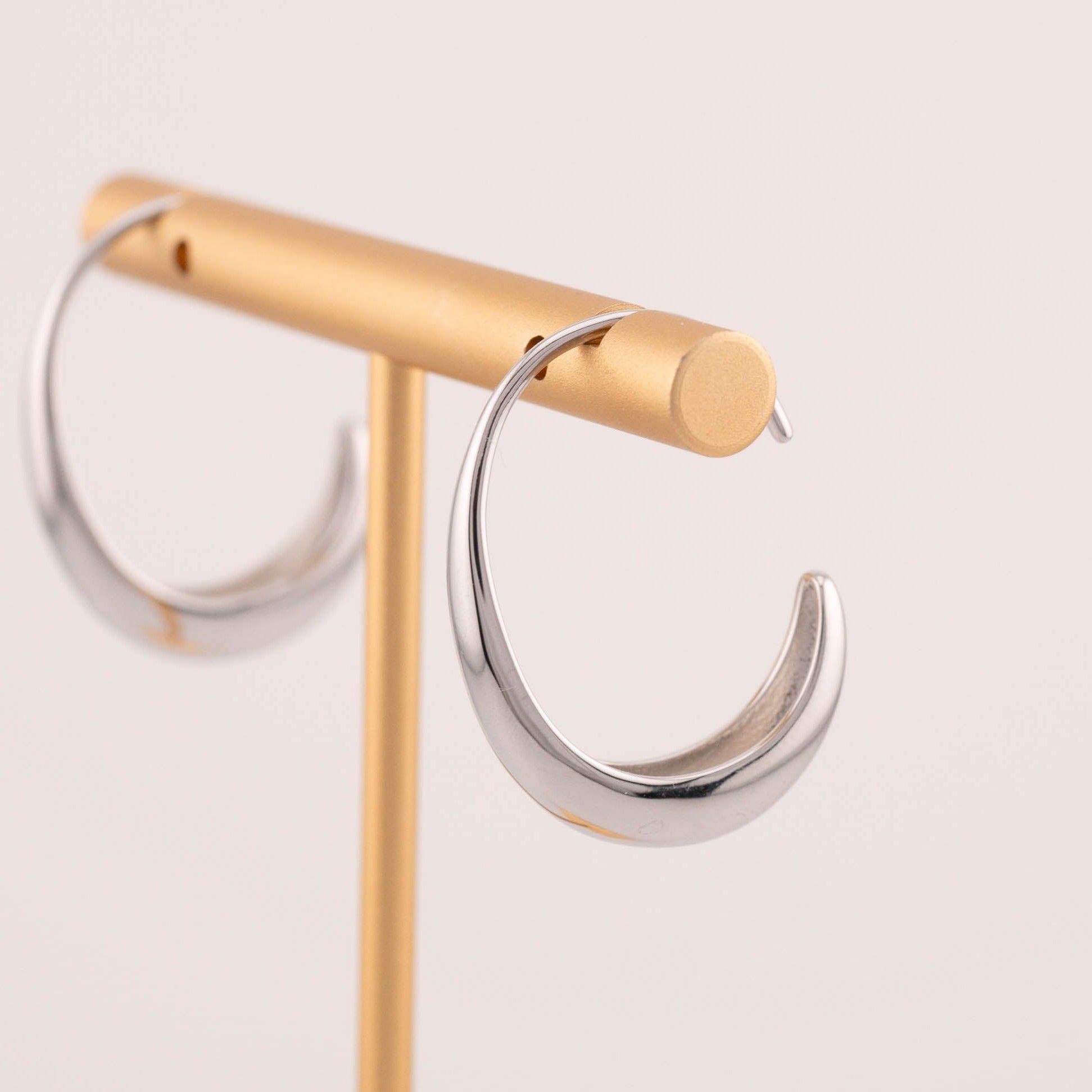 Minimalist medium sized silver ear hoops earrings staged on jewelry stand