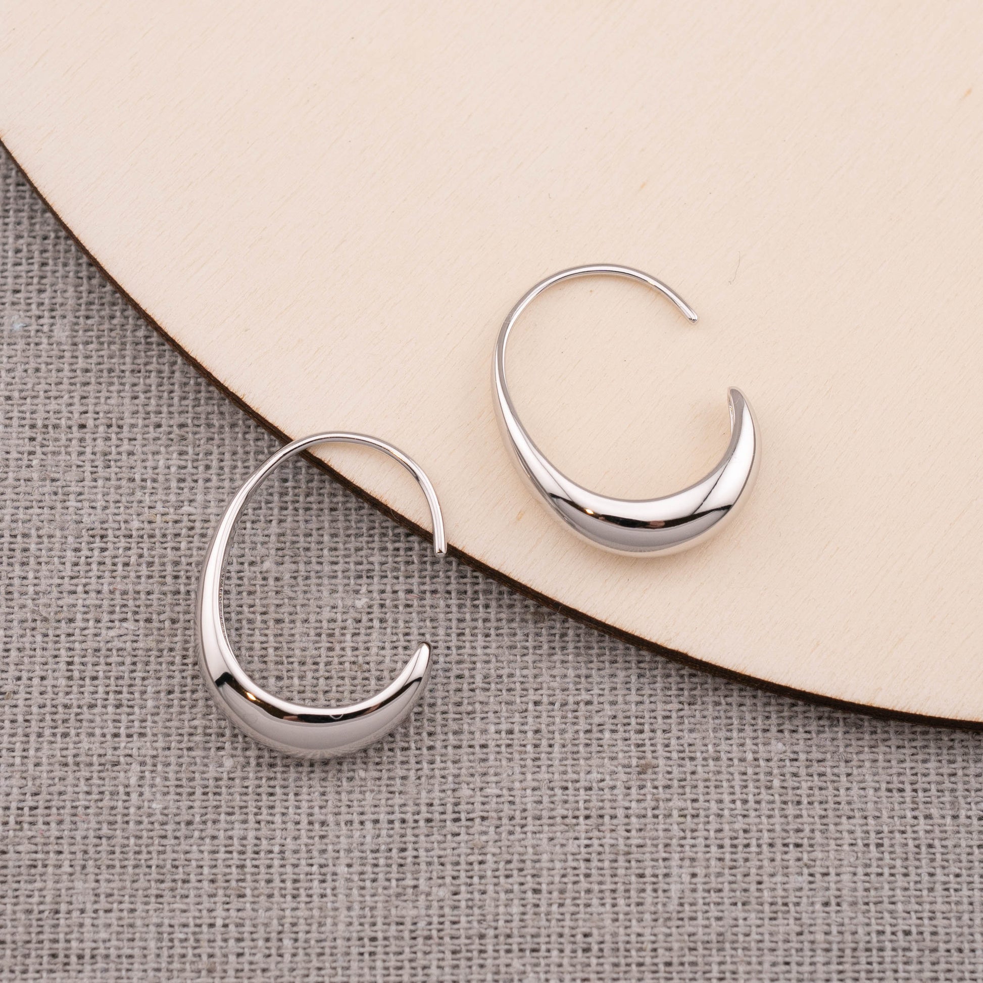 Top view of minimalist silver chunky hoop earrings elegantly staged on a table