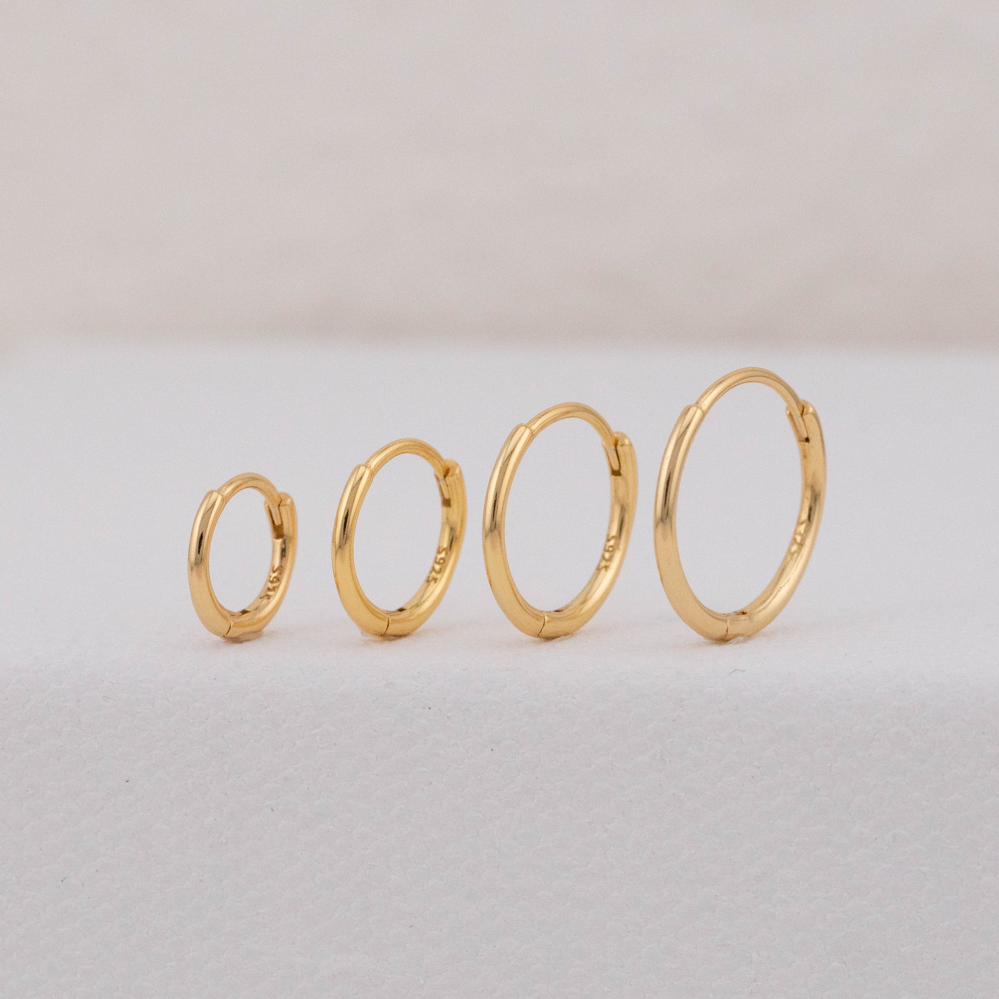 gold hoops in different sizes are displayed upright, showing stackable earring sets for 2 holes